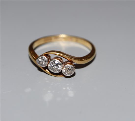 An 18ct and Pt, three stone diamond crossover ring, size M/N, gross 3 grams.